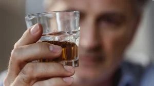 Man holding a glass of whiskey, illustrating the stages of alcoholism